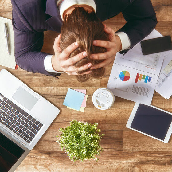 businessman in panic. a young man sits at his Desk and holds his hands on his head.